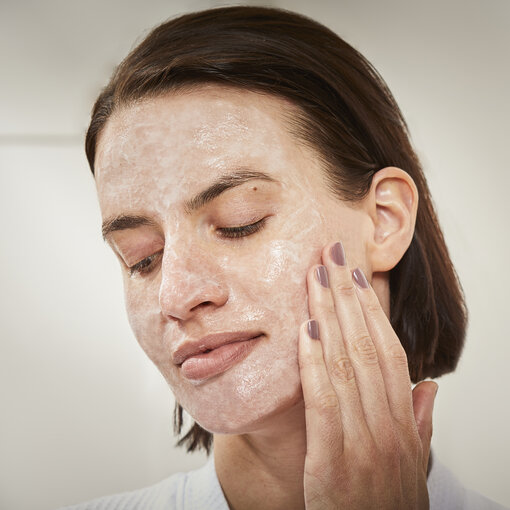 a woman applying a cleanser