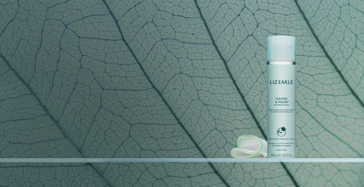 Liz Earle Cleanse and Polish on a shelf. In front of a microscopic image of a leaf