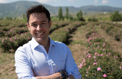 James Wong stood in a field with hedges and blooming pink flowers