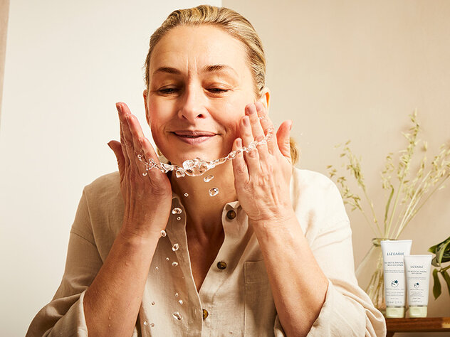 a mature woman applying a cleanser and washing her face